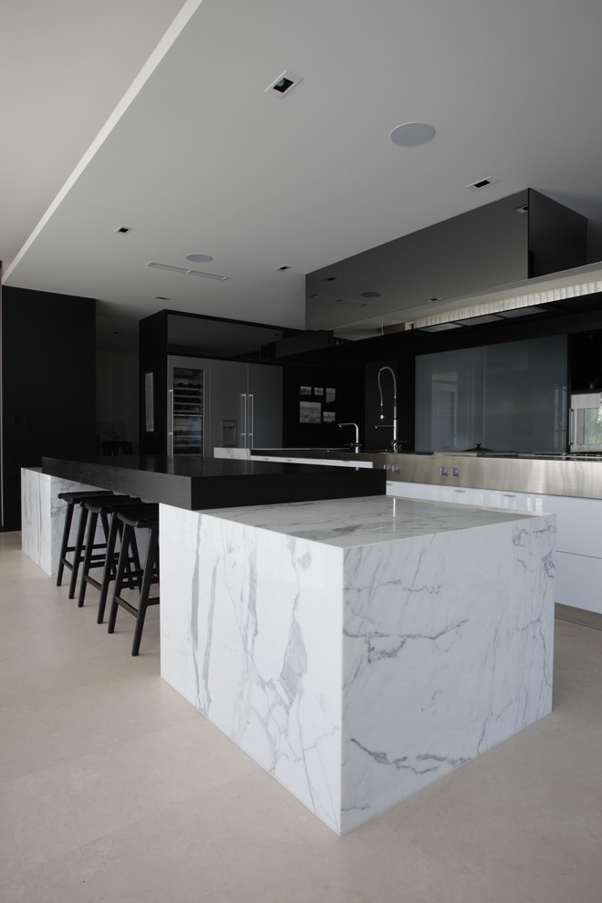 This is an example of a contemporary open plan kitchen in Perth with flat-panel cabinets, white cabinets, marble benchtops, glass sheet splashback, stainless steel appliances and multiple islands.