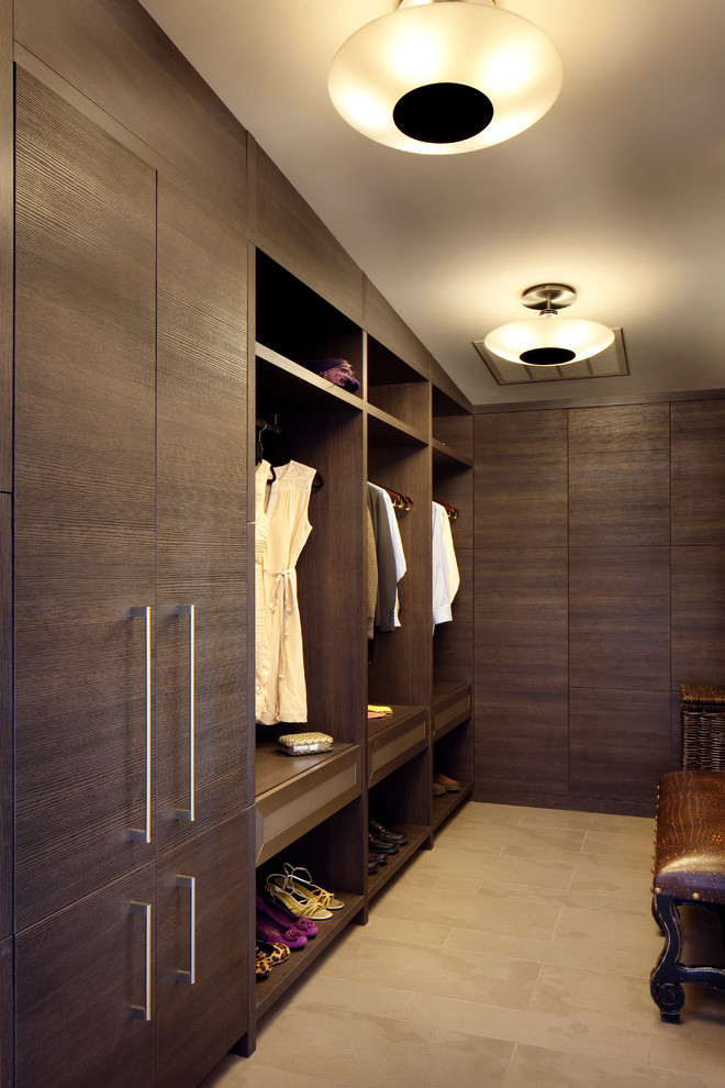 Photo of a large contemporary gender-neutral dressing room in Other with flat-panel cabinets, dark wood cabinets and travertine floors.