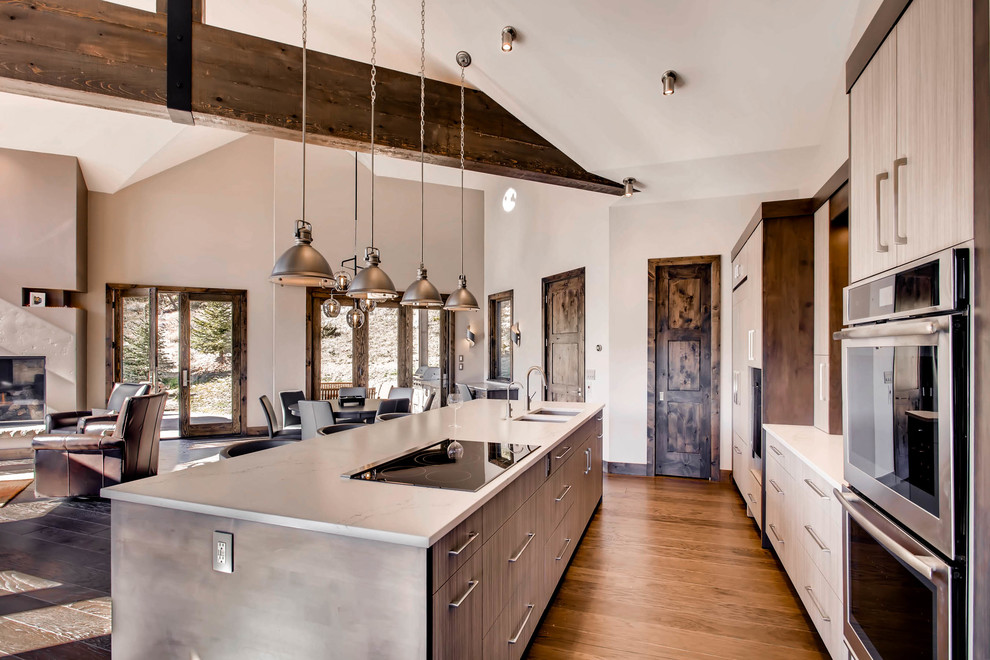 This is an example of a large modern single-wall open plan kitchen in Denver with an undermount sink, flat-panel cabinets, grey cabinets, marble benchtops, brown splashback, slate splashback, stainless steel appliances, dark hardwood floors, with island and brown floor.