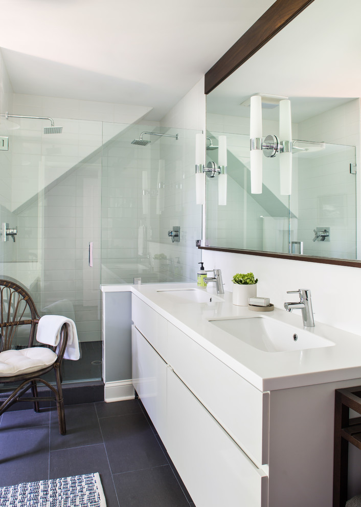 This is an example of a mid-sized contemporary master bathroom in Atlanta with an undermount sink, flat-panel cabinets, white cabinets, solid surface benchtops, a two-piece toilet, white tile, subway tile, white walls and porcelain floors.