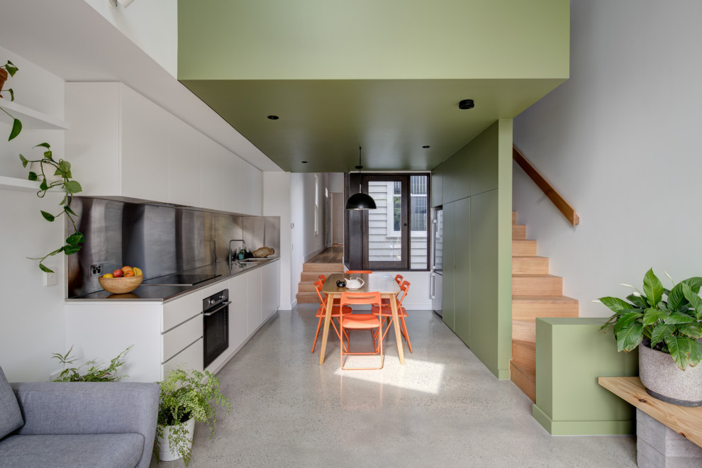 Inspiration for a contemporary open plan kitchen in Melbourne with an integrated sink, flat-panel cabinets, white cabinets, stainless steel benchtops, concrete floors and grey floor.