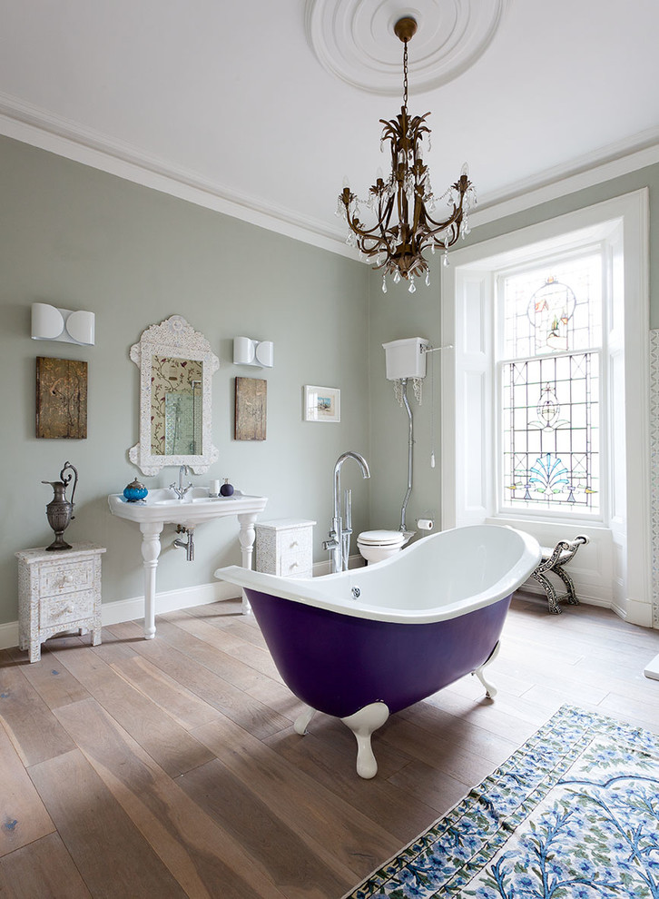 This is an example of a traditional bathroom in Glasgow with a console sink, a freestanding tub, a two-piece toilet, grey walls and medium hardwood floors.