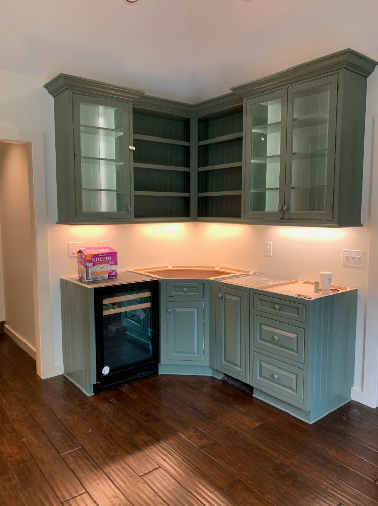 Example of a transitional u-shaped kitchen design with a farmhouse sink, raised-panel cabinets, green cabinets, soapstone countertops, stainless steel appliances and an island