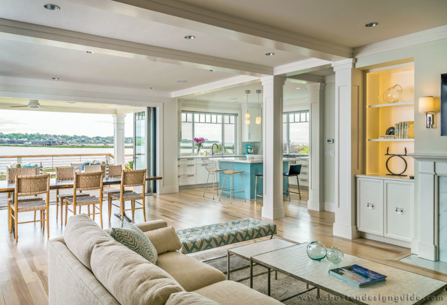 This is an example of a large beach style open concept living room in Burlington with white walls, light hardwood floors, a standard fireplace, a wood fireplace surround and a wall-mounted tv.