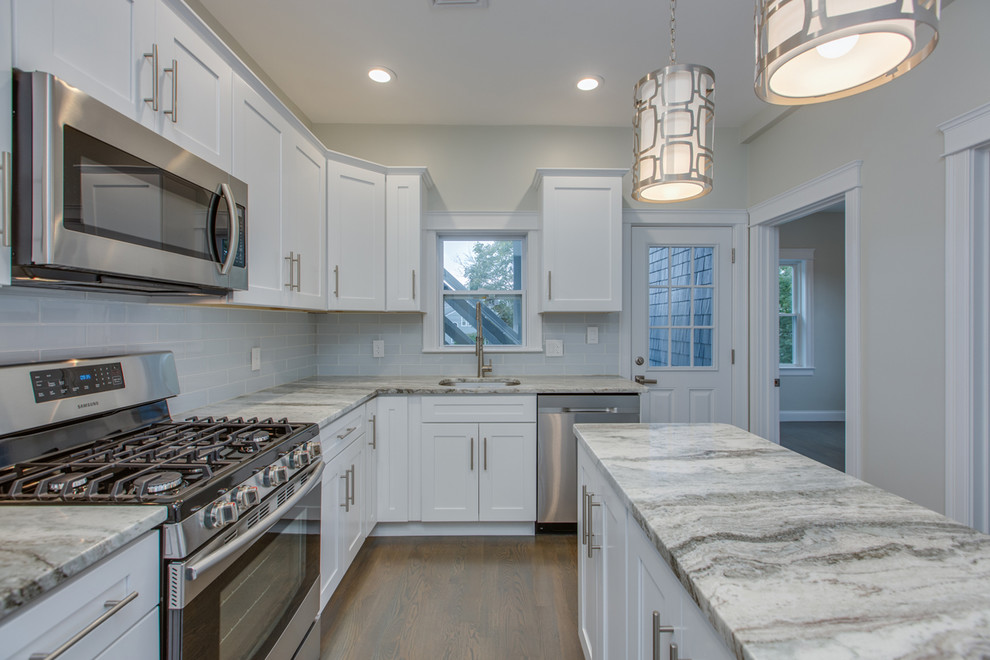 Inspiration for a mid-sized transitional l-shaped dark wood floor and brown floor enclosed kitchen remodel in Boston with an undermount sink, shaker cabinets, white cabinets, marble countertops, gray backsplash, subway tile backsplash, stainless steel appliances, an island and white countertops