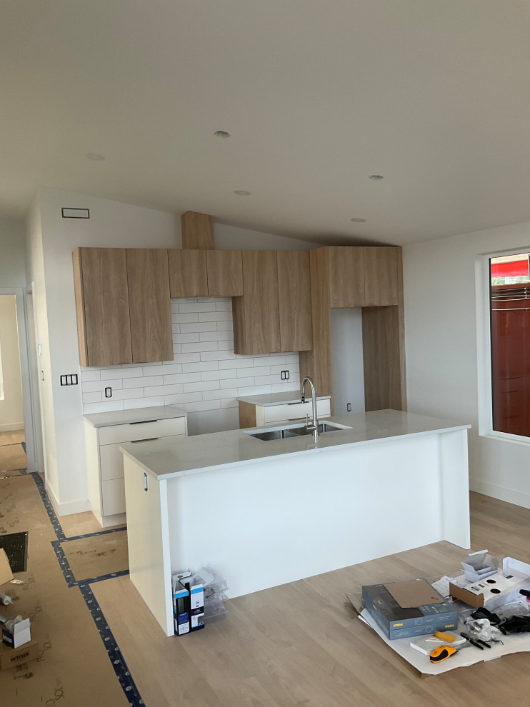 Modern kitchen with white shaker cabinets, large island, pendant lights, and sta