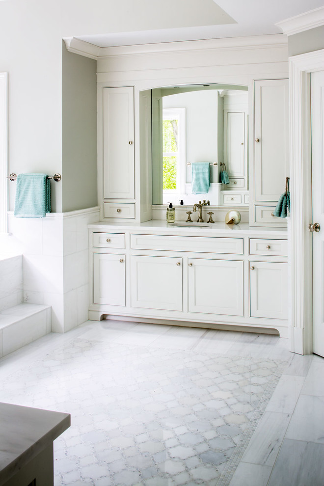 This is an example of a large beach style master bathroom in New York with recessed-panel cabinets, white cabinets, a drop-in tub, white tile, stone tile, green walls, marble floors and marble benchtops.