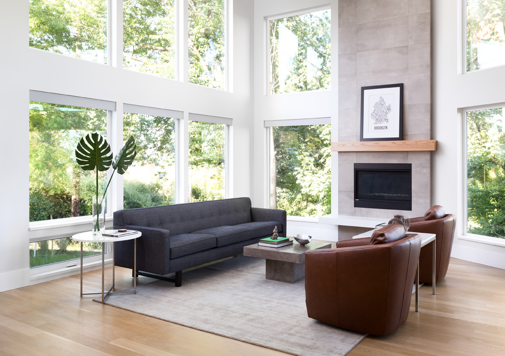 This is an example of a mid-sized contemporary open concept living room in Portland with white walls, light hardwood floors, a standard fireplace, a tile fireplace surround, no tv and beige floor.