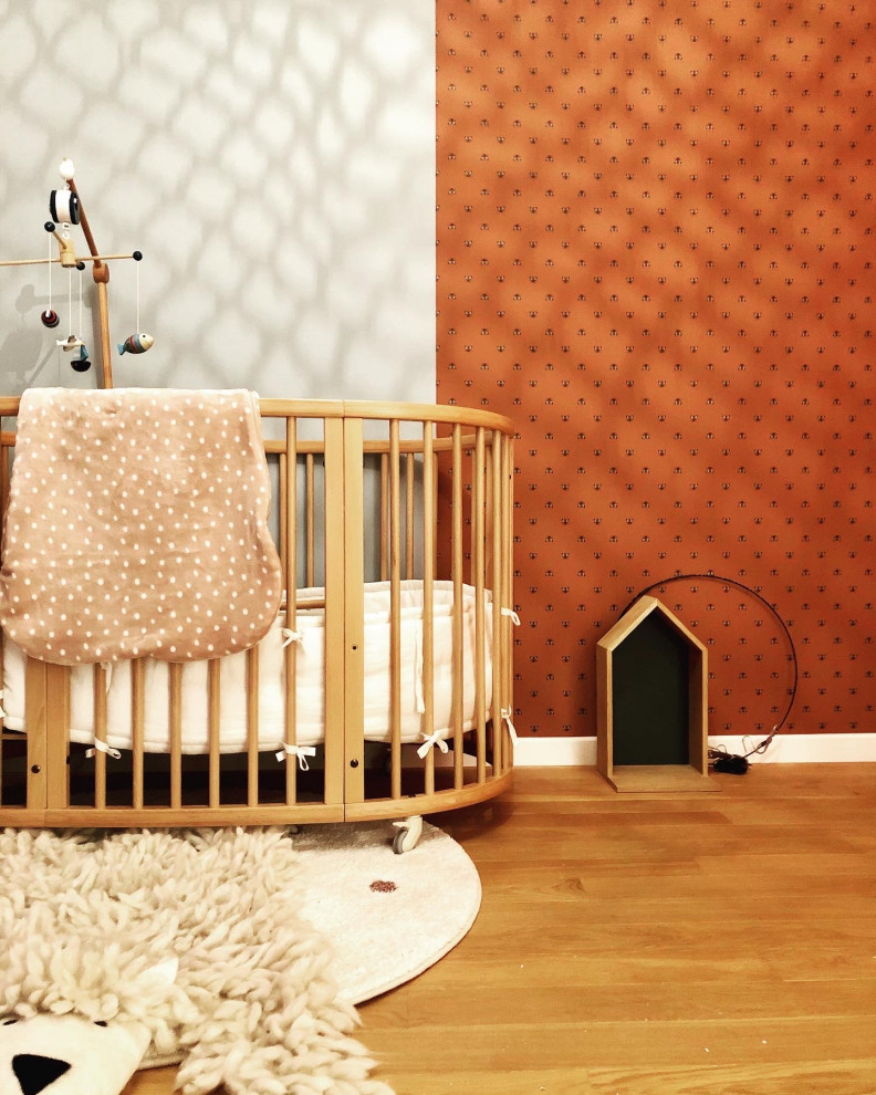 This is an example of a mid-sized scandinavian nursery for girls in Paris with blue walls, light hardwood floors and brown floor.