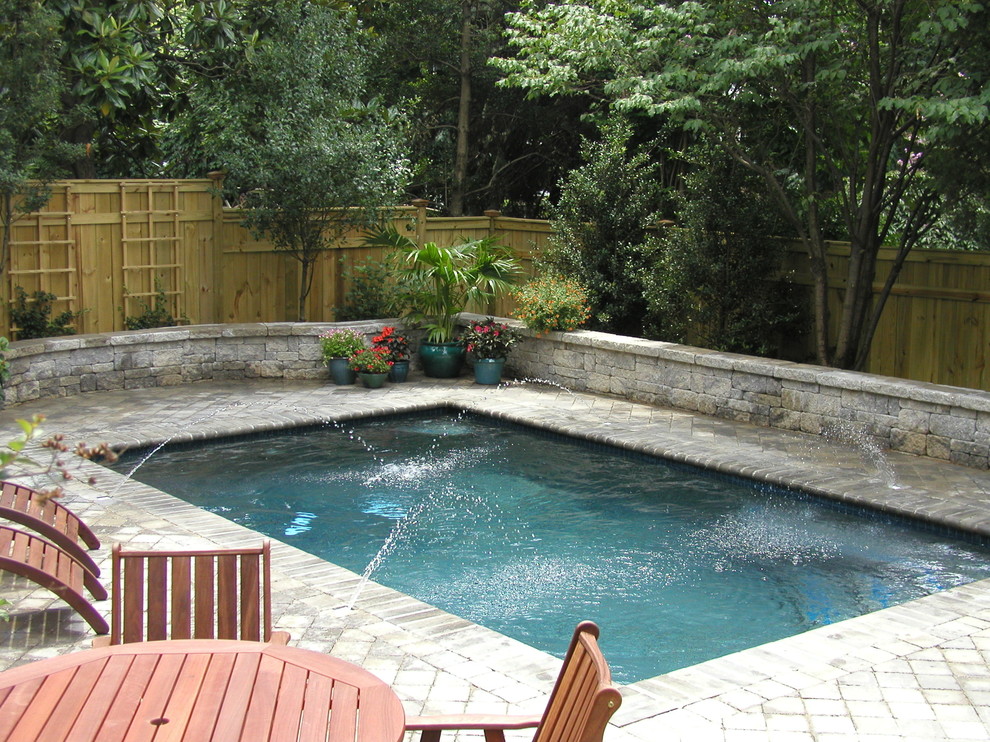 This is an example of a small traditional backyard rectangular lap pool in DC Metro with a water feature and concrete pavers.
