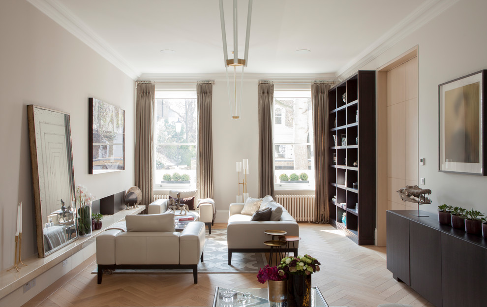 Photo of a contemporary enclosed living room in London with a library, beige walls, light hardwood floors, a standard fireplace, a stone fireplace surround and beige floor.