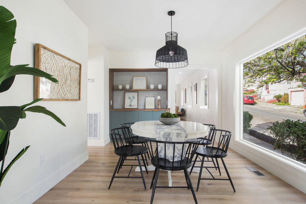 This is an example of a small scandinavian separate dining room in San Francisco with white walls and light hardwood floors.