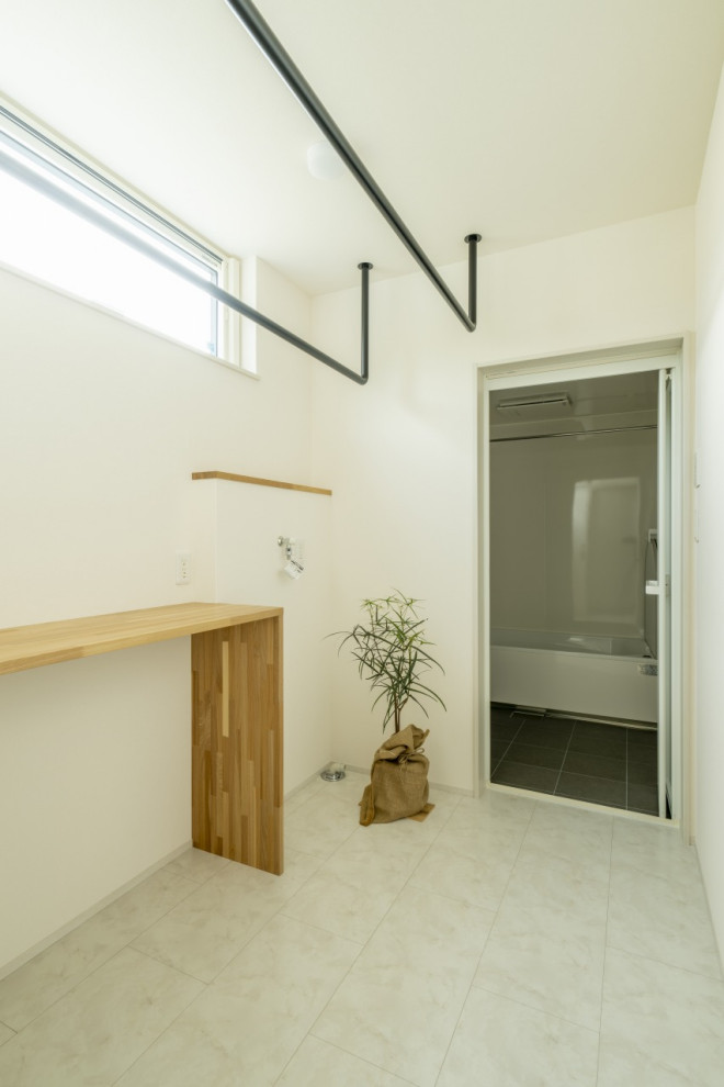 Foto på en mellanstor funkis tvättstuga, med vita väggar, mellanmörkt trägolv och brunt golv