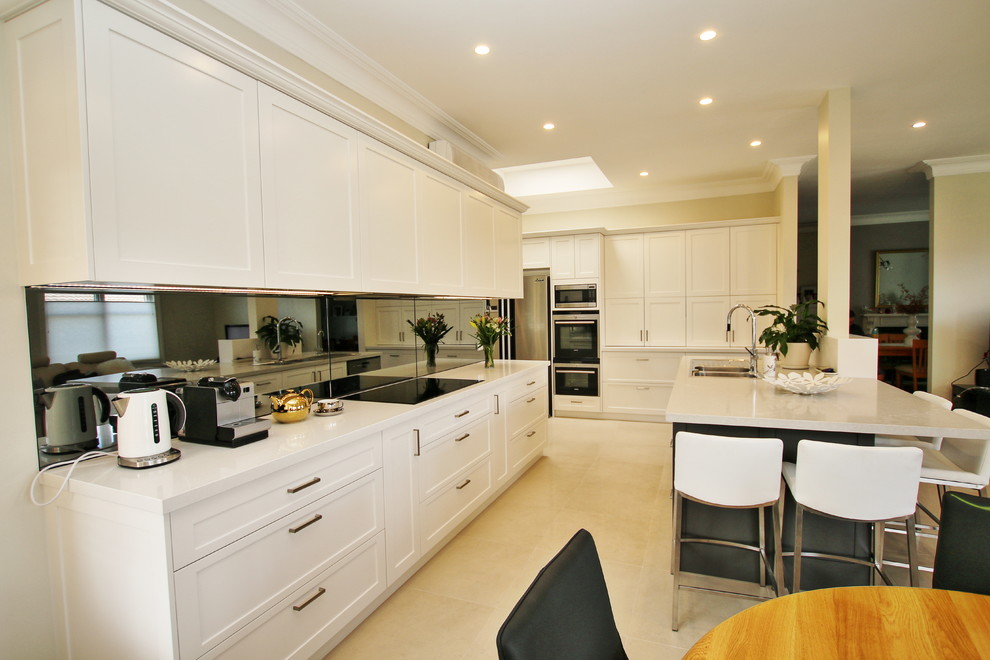 Inspiration for a large transitional l-shaped eat-in kitchen in Sydney with a drop-in sink, shaker cabinets, white cabinets, quartz benchtops, grey splashback, glass sheet splashback, stainless steel appliances, ceramic floors and with island.