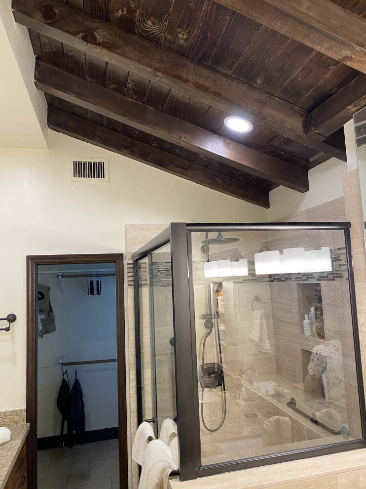 Immagine di una grande stanza da bagno padronale classica con ante in legno bruno, doccia alcova, lavabo sottopiano, porta doccia scorrevole, panca da doccia, due lavabi, mobile bagno incassato e travi a vista