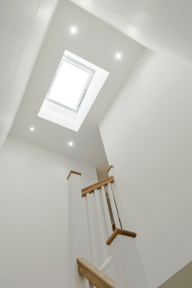 This is an example of a mid-sized modern wood u-shaped staircase in London with wood risers and wood railing.