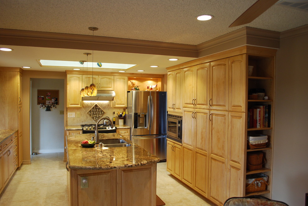 Photo of a traditional galley eat-in kitchen in Sacramento with an undermount sink, raised-panel cabinets, light wood cabinets, granite benchtops, beige splashback, stone tile splashback, stainless steel appliances, porcelain floors and with island.