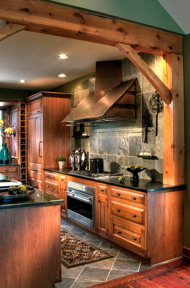 Inspiration for a rustic slate floor kitchen remodel with an undermount sink, light wood cabinets, paneled appliances, stone tile backsplash and an island
