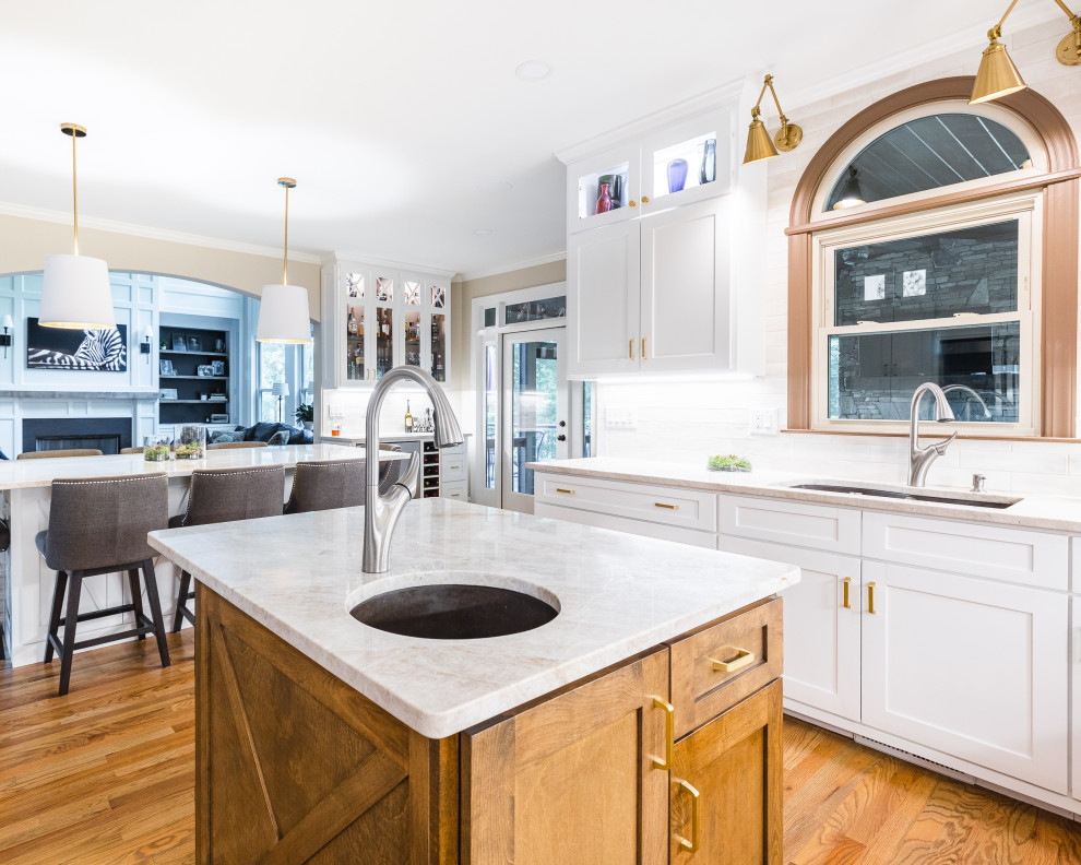 This is an example of an expansive modern u-shaped eat-in kitchen in Atlanta with an undermount sink, shaker cabinets, white cabinets, quartzite benchtops, white splashback, ceramic splashback, stainless steel appliances, medium hardwood floors, multiple islands, brown floor and beige benchtop.