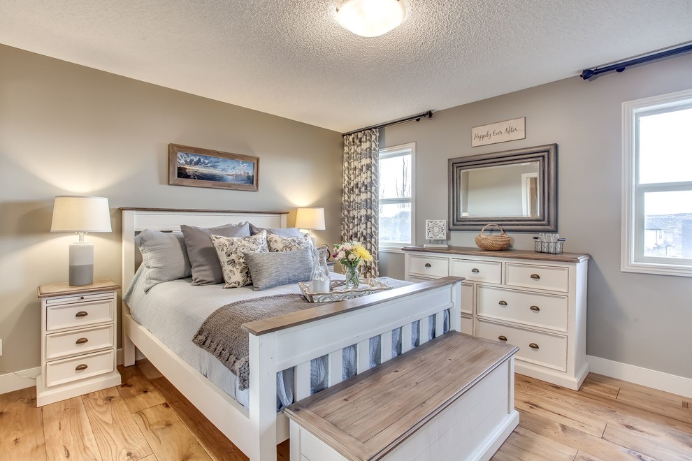 Photo of a mid-sized country master bedroom in Calgary with beige walls and medium hardwood floors.
