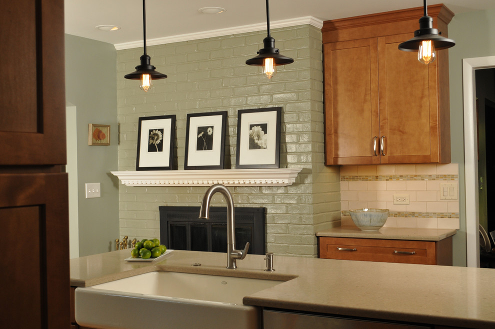 Example of a transitional light wood floor kitchen design in Chicago with a farmhouse sink, medium tone wood cabinets, quartz countertops, beige backsplash, stainless steel appliances and an island