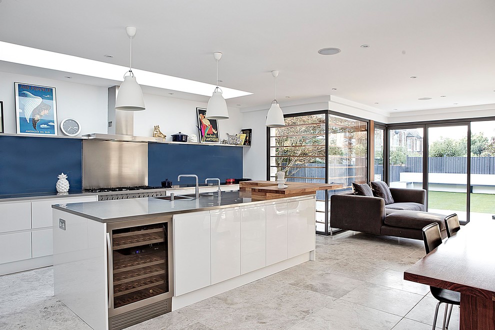 Inspiration for a mid-sized contemporary single-wall open plan kitchen in Wiltshire with a double-bowl sink, flat-panel cabinets, white cabinets, stainless steel benchtops, metal splashback, stainless steel appliances, with island, blue splashback, beige floor and grey benchtop.