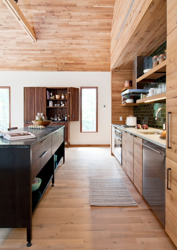 Eat-in kitchen - contemporary light wood floor eat-in kitchen idea in New York with an undermount sink, flat-panel cabinets, medium tone wood cabinets, green backsplash, stainless steel appliances and an island