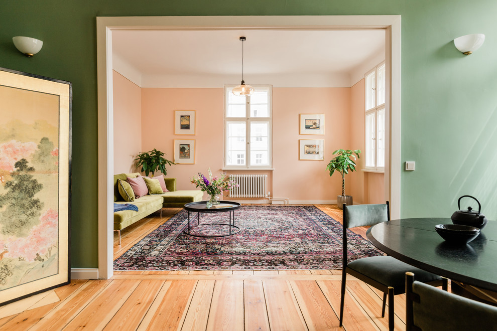 This is an example of a large transitional enclosed living room in Berlin with pink walls, medium hardwood floors and brown floor.