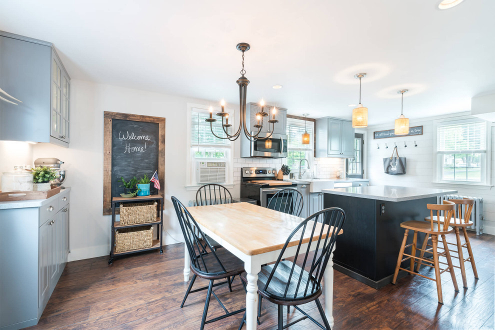 Design ideas for a country eat-in kitchen in Bridgeport with a farmhouse sink, raised-panel cabinets, grey cabinets, white splashback, subway tile splashback, stainless steel appliances, laminate floors, with island, brown floor and grey benchtop.