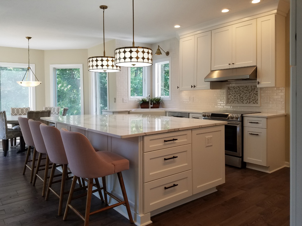 Eat-in kitchen - large transitional u-shaped medium tone wood floor and gray floor eat-in kitchen idea with a farmhouse sink, shaker cabinets, white cabinets, quartz countertops, white backsplash, subway tile backsplash, stainless steel appliances, an island and white countertops