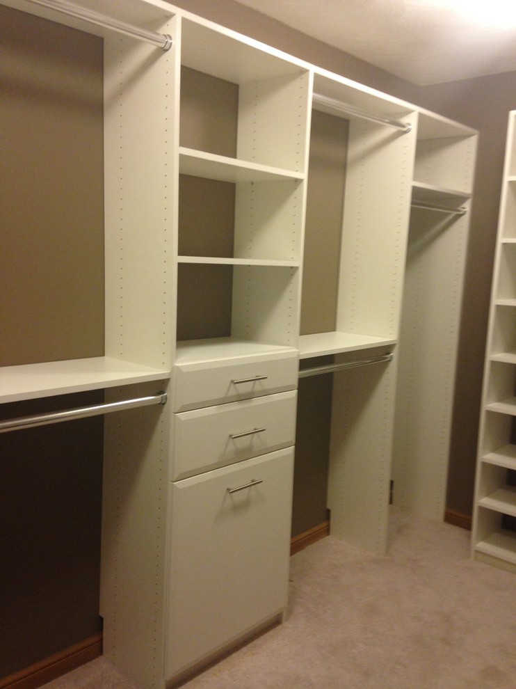 Inspiration for a mid-sized contemporary gender-neutral walk-in wardrobe in Columbus with flat-panel cabinets, white cabinets and carpet.