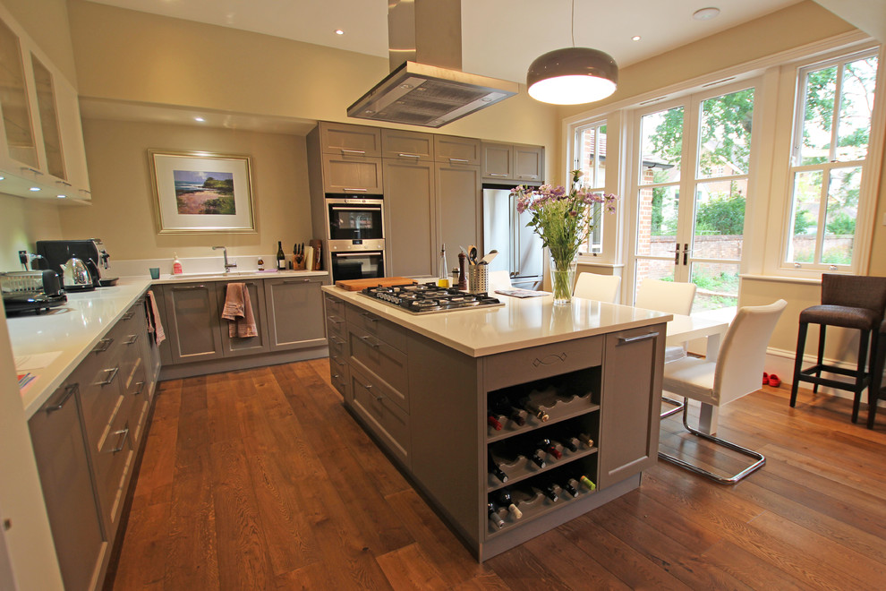 Country kitchen in London with grey cabinets, quartz benchtops, medium hardwood floors, with island and shaker cabinets.