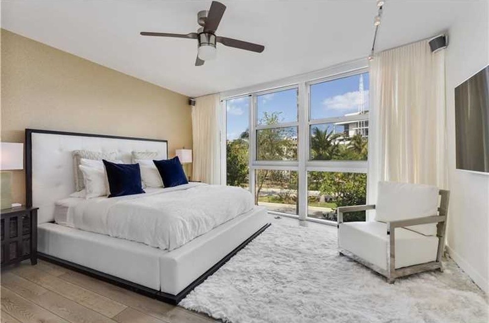 Large contemporary master bedroom in Miami with white walls, medium hardwood floors and no fireplace.