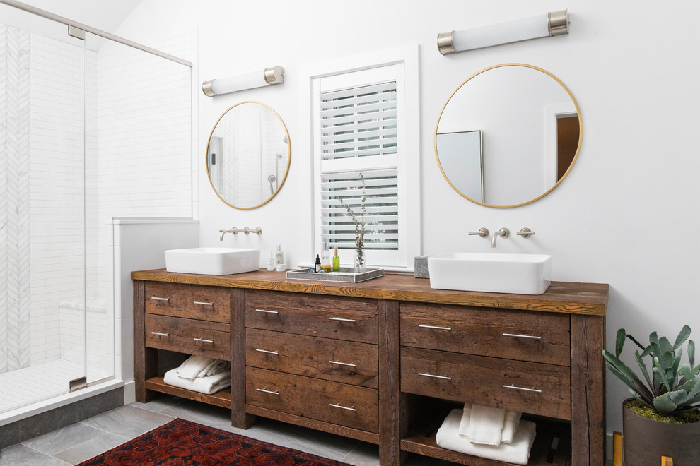 Country master bathroom in Boston with medium wood cabinets, an alcove shower, white tile, white walls, a vessel sink, wood benchtops, grey floor, a hinged shower door, brown benchtops and flat-panel cabinets.