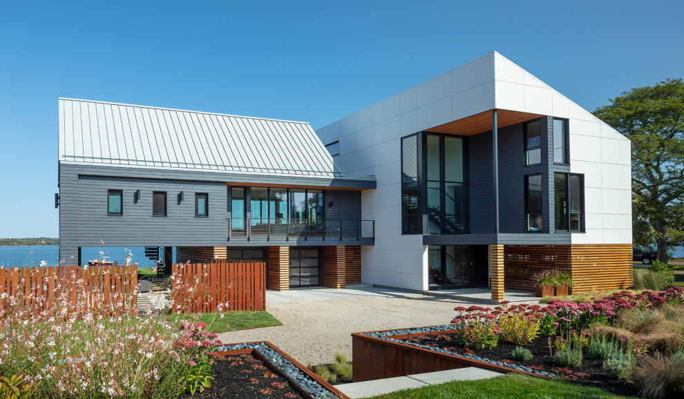 Стильный дизайн: трехэтажный, серый частный загородный дом в современном стиле с комбинированной облицовкой, двускатной крышей и металлической крышей - последний тренд