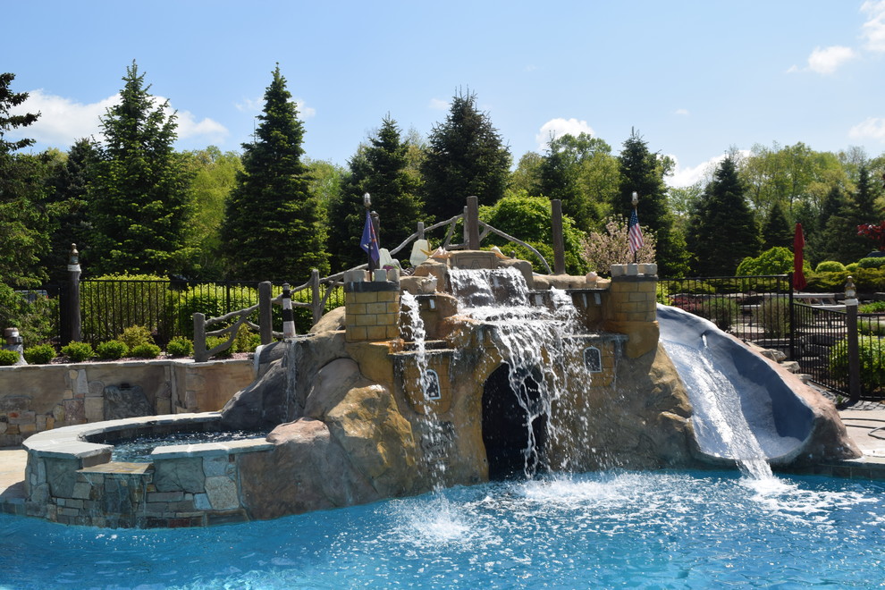 Expansive transitional backyard custom-shaped pool in Detroit with a water slide and stamped concrete.