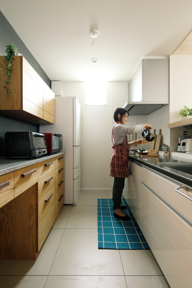 他の地域にある小さなアジアンスタイルのおしゃれなキッチン (一体型シンク、白いキャビネット、ステンレスカウンター、白いキッチンパネル、白い床、グレーのキッチンカウンター、磁器タイルの床) の写真