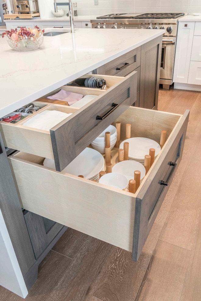 Inspiration for a mid-sized transitional u-shaped medium tone wood floor and brown floor home design remodel in Calgary with an undermount sink, flat-panel cabinets, white cabinets, marble countertops, gray backsplash, ceramic backsplash, paneled appliances and an island