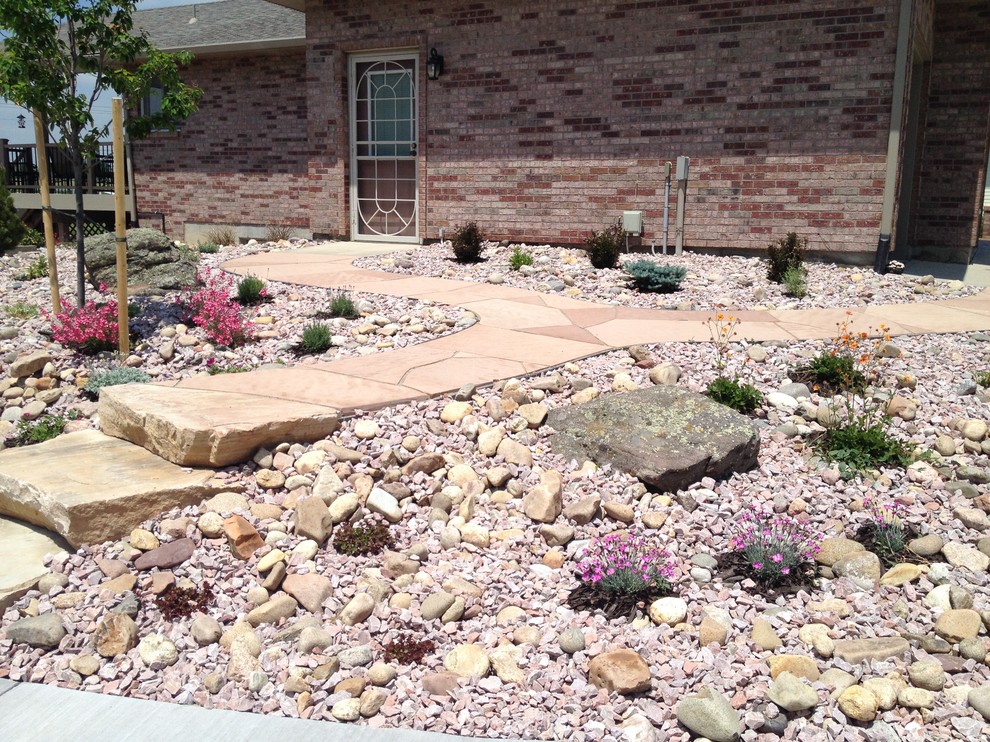 Photo of a mid-sized arts and crafts sloped full sun xeriscape in Denver with a retaining wall and natural stone pavers.