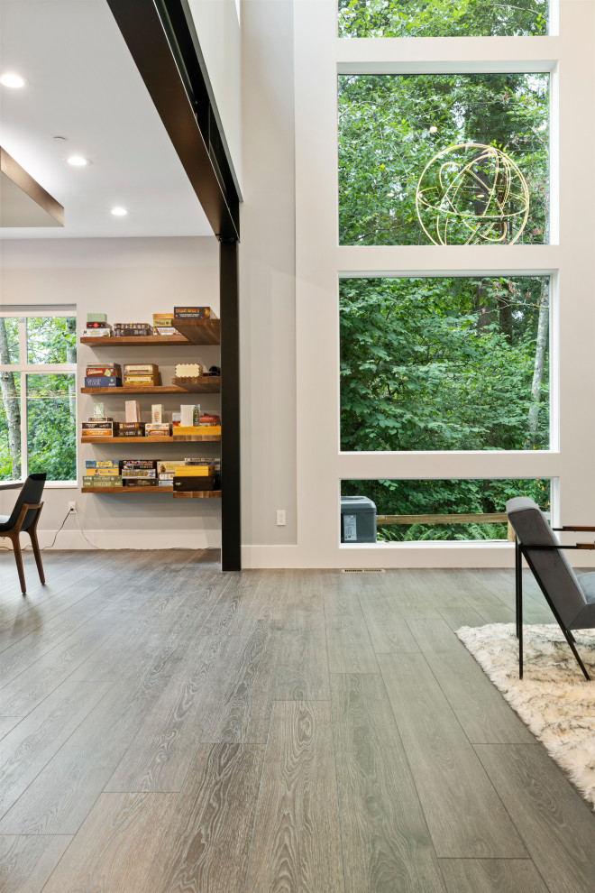Réalisation d'un grand salon minimaliste ouvert avec une salle de réception, un mur gris, un sol en vinyl, une cheminée standard, un manteau de cheminée en pierre, un sol gris et un plafond voûté.