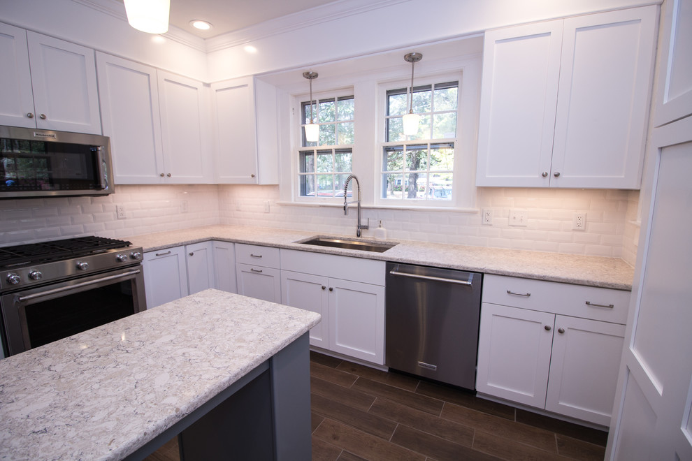 Small u-shaped ceramic tile eat-in kitchen photo with an undermount sink, shaker cabinets, white cabinets, quartz countertops, white backsplash, subway tile backsplash, stainless steel appliances, an island and white countertops