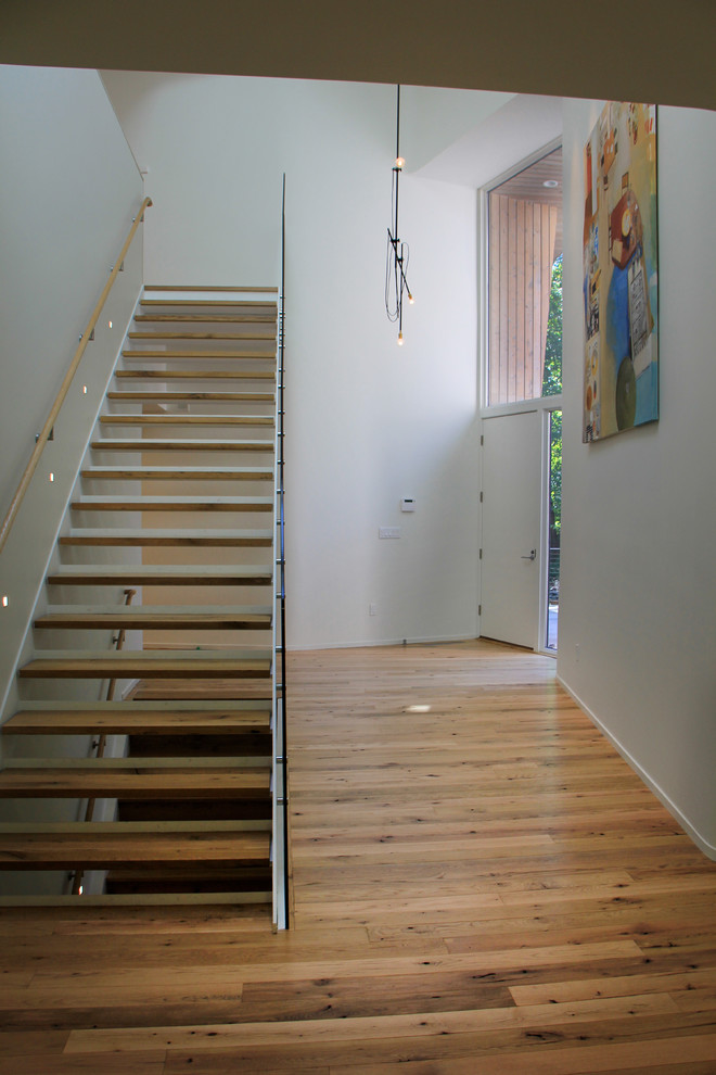 Large contemporary wood floating staircase in New York with metal risers.