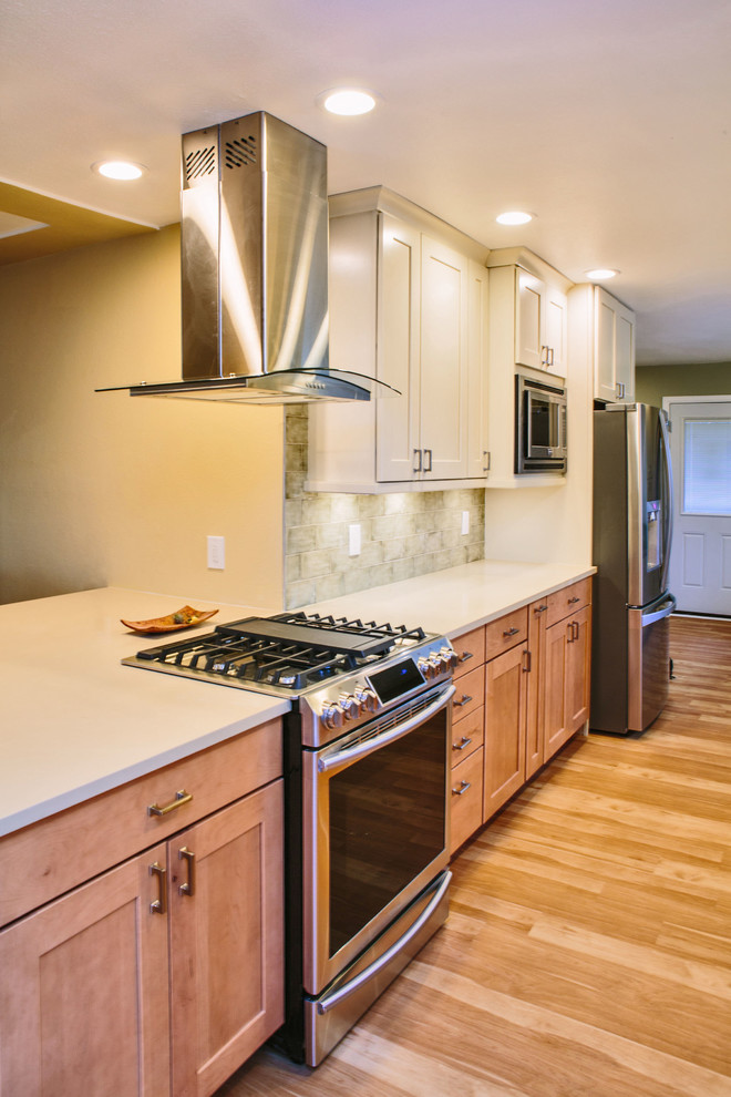 Inspiration for a large galley eat-in kitchen in Denver with an undermount sink, shaker cabinets, light wood cabinets, quartz benchtops, green splashback, ceramic splashback, stainless steel appliances, laminate floors and a peninsula.