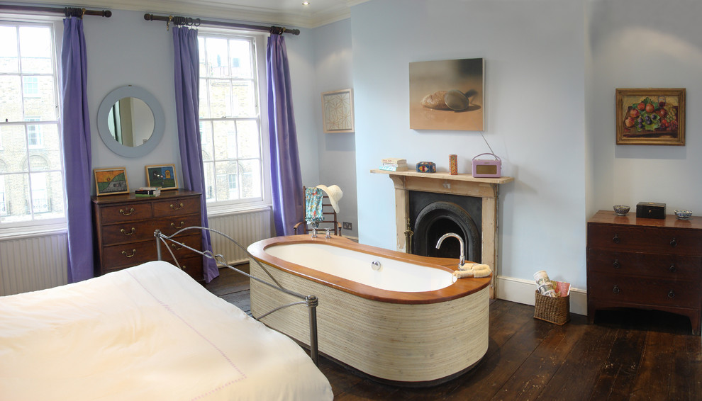 Inspiration for an eclectic master bedroom in London with blue walls, dark hardwood floors and a standard fireplace.
