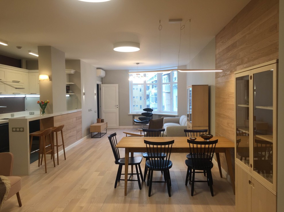 This is an example of a scandinavian kitchen/dining combo in Moscow with grey walls, light hardwood floors, no fireplace, brown floor and wood walls.