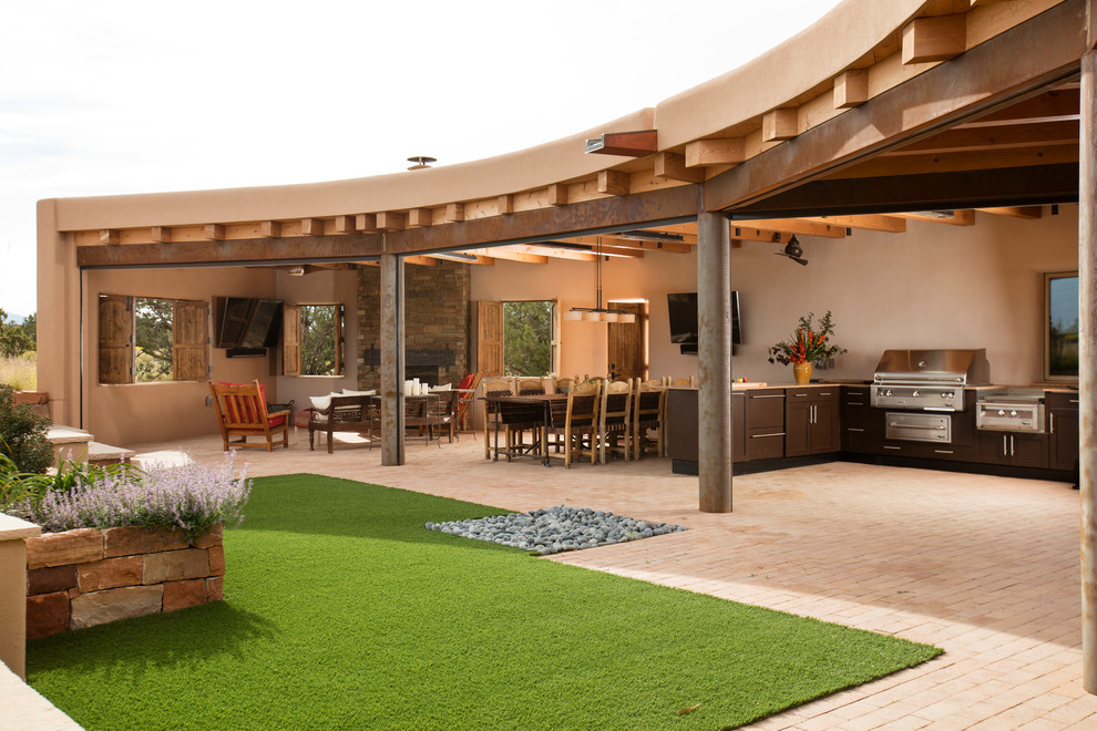 Photo of a backyard patio in Albuquerque with with fireplace, natural stone pavers and a pergola.