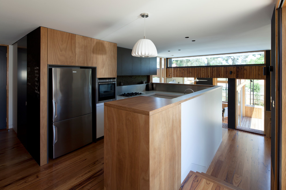Design ideas for a mid-sized contemporary u-shaped open plan kitchen in Melbourne with a double-bowl sink, white cabinets, quartz benchtops, metallic splashback, stainless steel appliances and medium hardwood floors.
