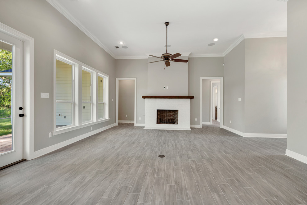 Inspiration for a traditional open concept living room in New Orleans with grey walls, ceramic floors, a standard fireplace, a brick fireplace surround and grey floor.