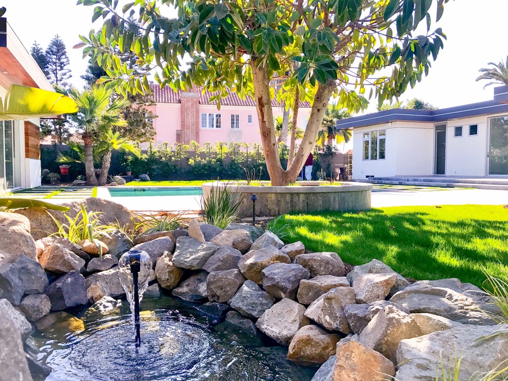 This is an example of a large contemporary backyard full sun formal garden for summer in San Diego with decking, a water feature and a wood fence.
