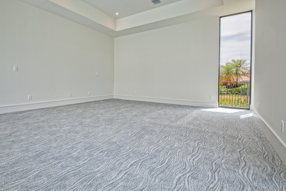 This is an example of a large modern master bedroom in Miami with white walls, carpet, no fireplace and grey floor.